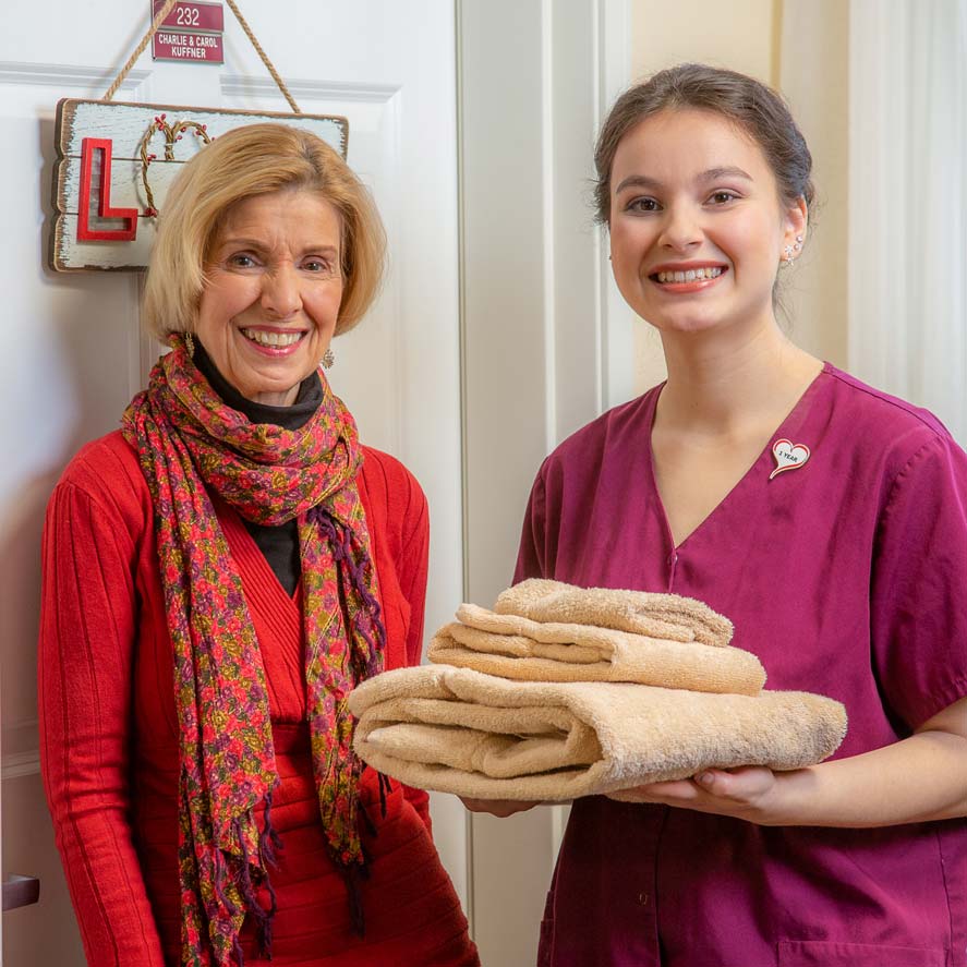 A team member delivering fresh linens to a resident at Meadowlark Estates